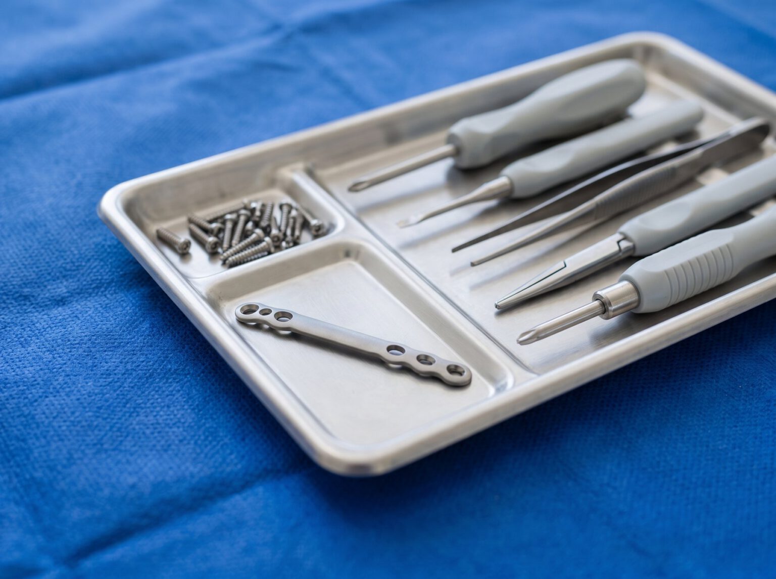 A tray of surgical instruments, plates and screws